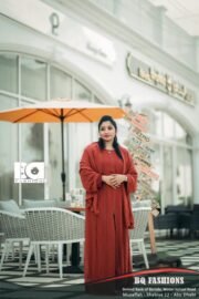 Young woman modeling terracotta colored abaya outdoors - loose fitting rust orange modest dress with long sleeves and flowing silhouette