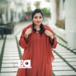 Young woman modeling terracotta colored abaya outdoors - loose fitting rust orange modest dress with long sleeves and flowing silhouette