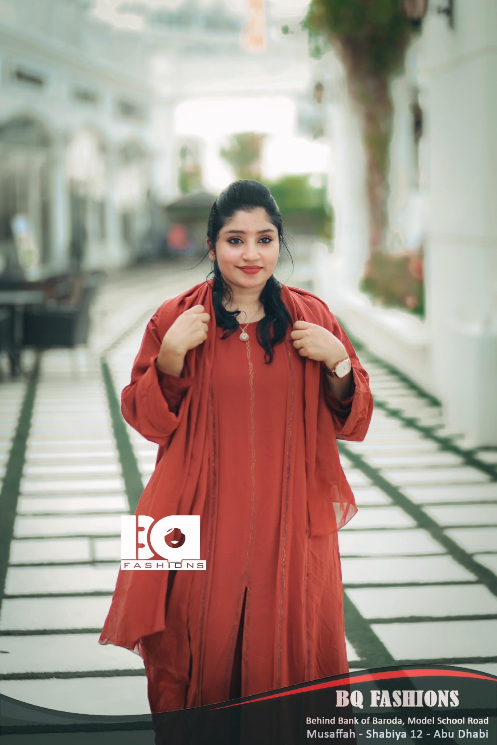 Young woman modeling terracotta colored abaya outdoors - loose fitting rust orange modest dress with long sleeves and flowing silhouette