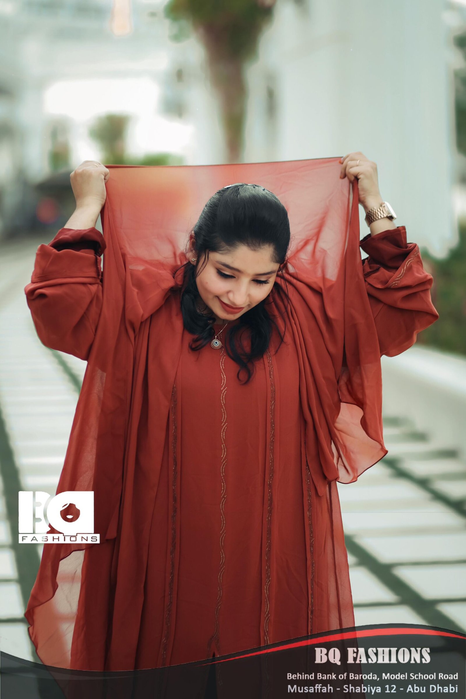 Young woman modeling terracotta colored abaya outdoors - loose fitting rust orange modest dress with long sleeves and flowing silhouette